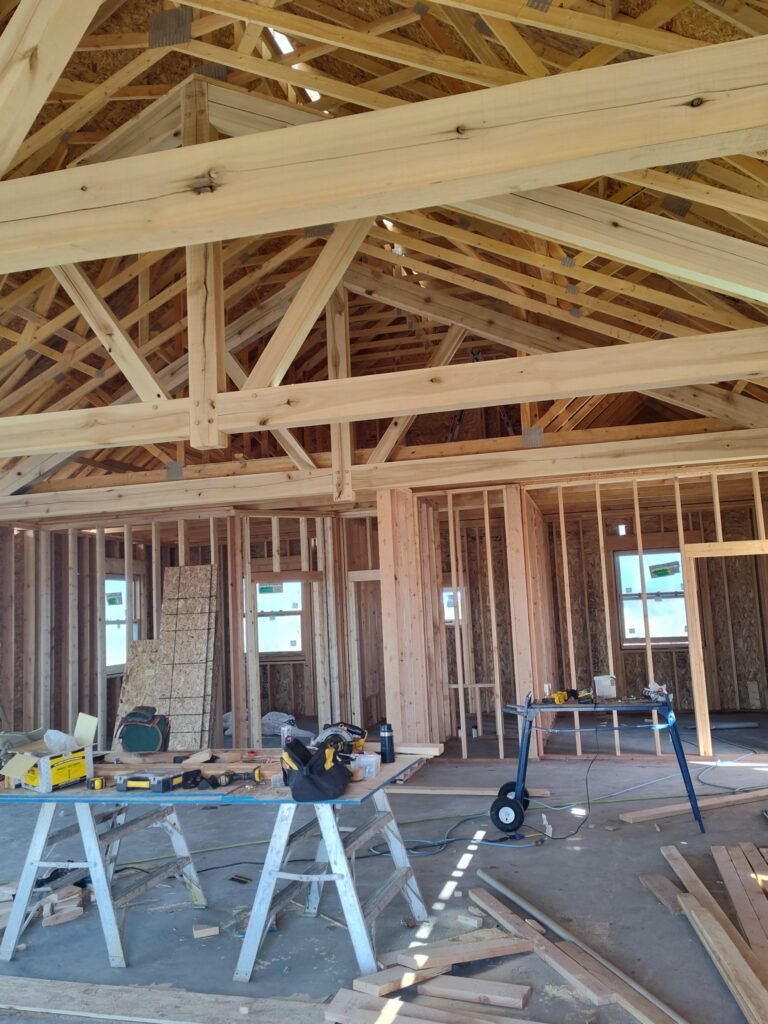 Construction contractors working on a new house build in Montana with only the home studs showing and power tools